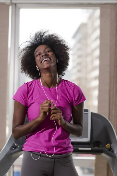 Afro americano mulher correndo em uma esteira — Fotografia de Stock