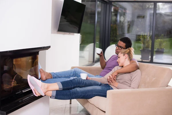 Pareja joven multiétnica frente a la chimenea — Foto de Stock