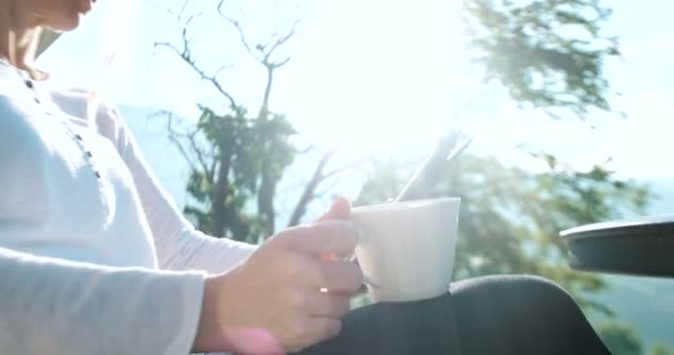 Молодая женщина пьет кофе на террасе — стоковое видео