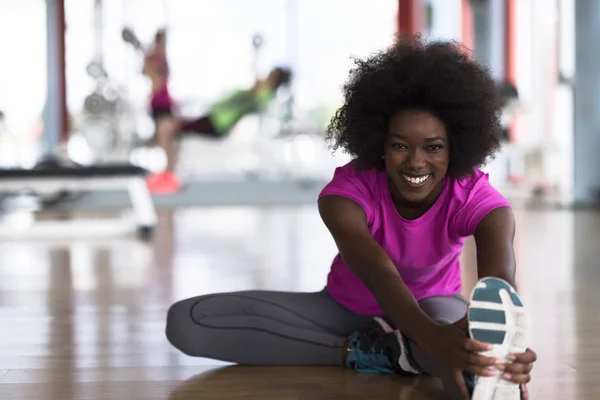 Kvinna i ett gym stretching och värmer upp — Stockfoto