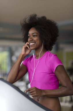 bir koşu bandı üzerinde çalışan afro Amerikalı kadın