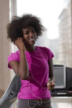 bir koşu bandı üzerinde çalışan afro Amerikalı kadın