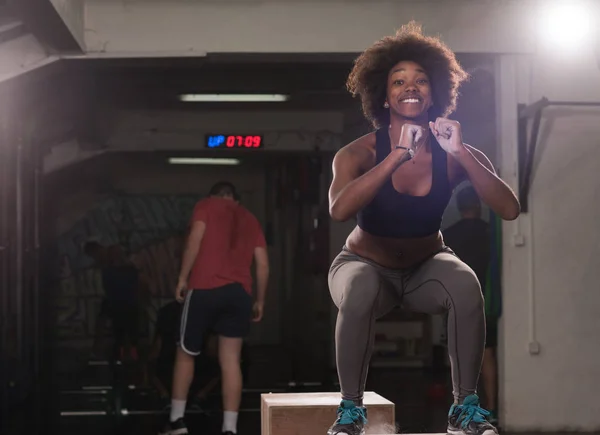 Atleta feminina preta está realizando saltos caixa no ginásio — Fotografia de Stock