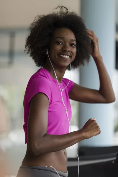 Afro americano mulher correndo em uma esteira — Fotografia de Stock