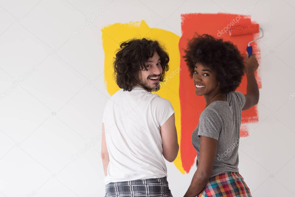 multiethnic couple painting interior wall