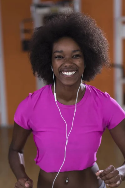 Bir koşu bandı üzerinde çalışan afro Amerikalı kadın — Stok fotoğraf