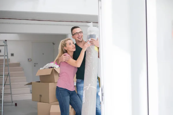 Pareja llevando una alfombra mudándose a un nuevo hogar — Foto de Stock