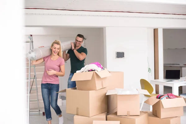 Pareja llevando una alfombra mudándose a un nuevo hogar — Foto de Stock