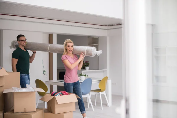 Casal carregando um tapete se mudando para casa nova — Fotografia de Stock