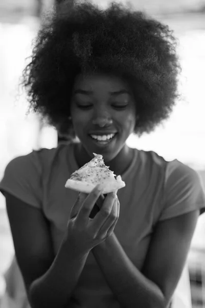 Donna con acconciatura afro mangiare gustosa fetta di pizza — Foto Stock