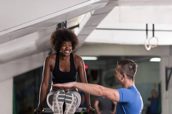 Black woman doing parallel bars Exercise with trainer — Stock Photo, Image