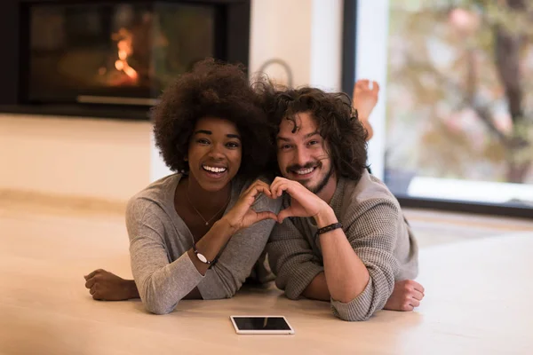 Multiethnic couple showing a heart with their hands on the floor — Stock Photo, Image