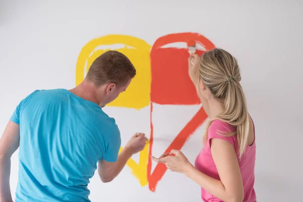 Пара рисует сердце на стене — стоковое фото