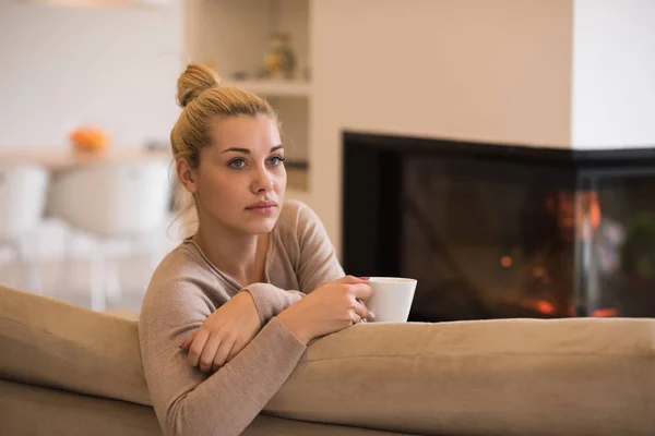 Kobieta z kubkiem w pobliżu kominek — Zdjęcie stockowe