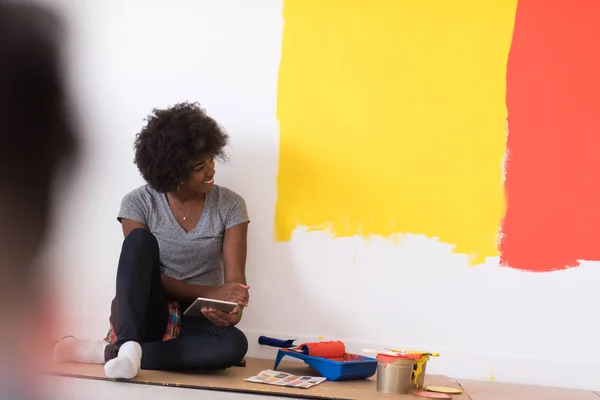 Černá samice malíř sedí na podlaze — Stock fotografie