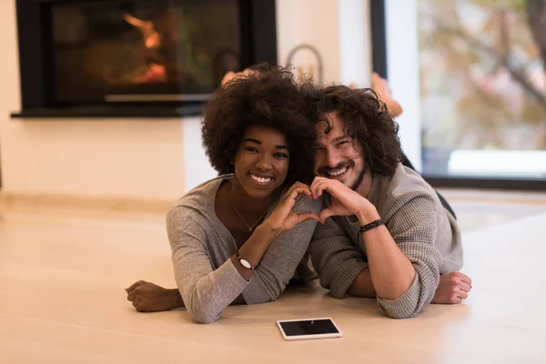 Couple multiethnique montrant un cœur avec les mains sur le sol — Photo