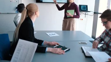 İş adamları parlak ofiste toplanıp iş planları yapıyorlar.