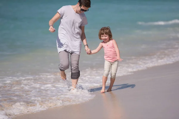 Mor och dotter springer på stranden — Stockfoto