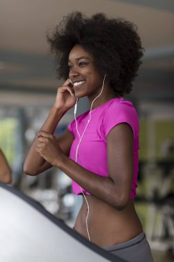 bir koşu bandı üzerinde çalışan afro Amerikalı kadın