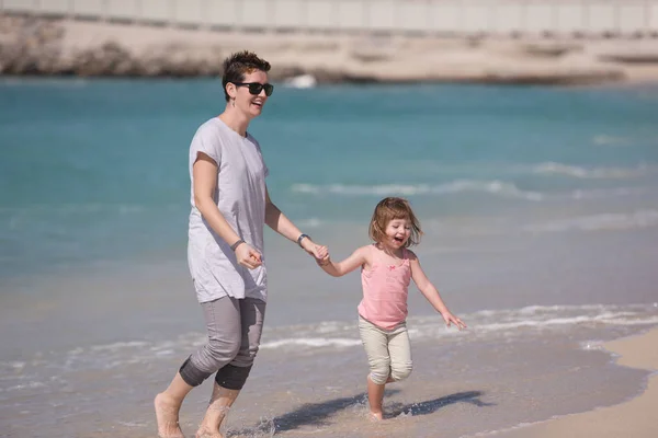 Mor och dotter springer på stranden — Stockfoto