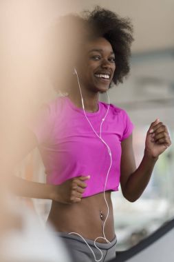 bir koşu bandı üzerinde çalışan afro Amerikalı kadın