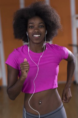 bir koşu bandı üzerinde çalışan afro Amerikalı kadın