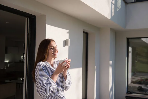 Vrouw in een badjas genieten van koffie in de ochtend — Stockfoto