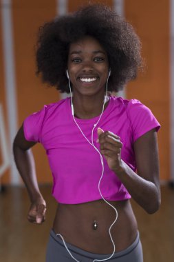 bir koşu bandı üzerinde çalışan afro Amerikalı kadın
