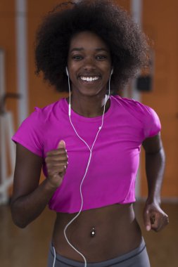 bir koşu bandı üzerinde çalışan afro Amerikalı kadın