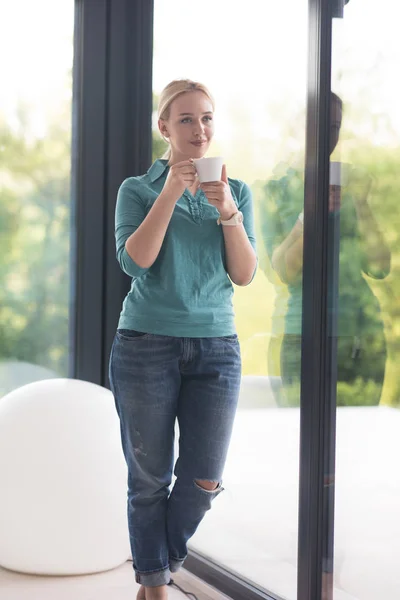 Ung kvinna dricka morgonkaffe vid fönstret — Stockfoto