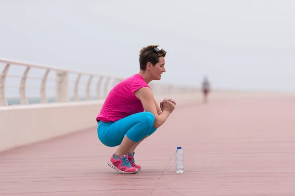 Woman stretching and warming up on the promenade — Stock Photo, Image