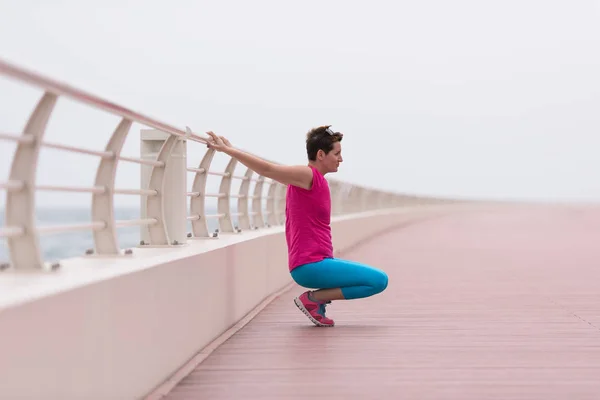 Vrouw rekken en opwarmen op de promenade — Stockfoto