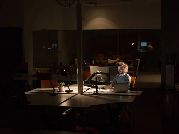 Людина працює на комп'ютері в темному офісі — стокове фото