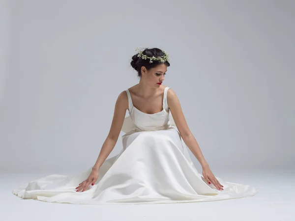 Ung brud sitter i en bröllopsklänning — Stockfoto