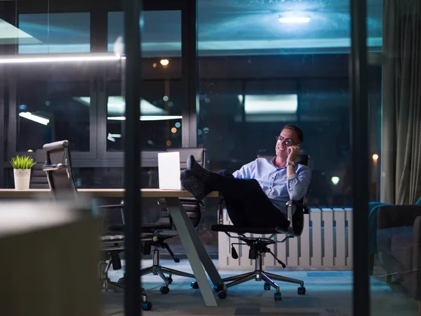 Uomo d'affari che utilizza il telefono cellulare in ufficio scuro — Foto Stock