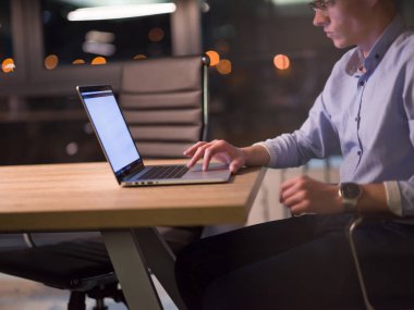 karanlık ofiste dizüstü bilgisayarda çalışan adam