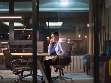 karanlık ofiste dizüstü bilgisayarda çalışan adam