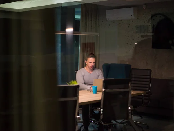 Man working on laptop in dark office — Stock Photo, Image