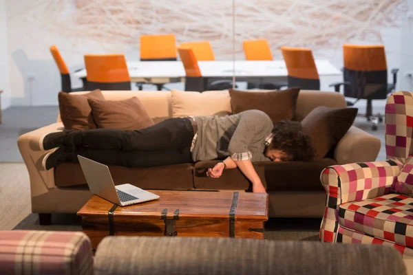 Hombre durmiendo en un sofá en una oficina creativa — Foto de Stock