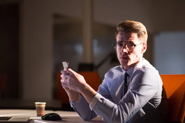 暗いオフィスで携帯電話を使用している人 — ストック写真