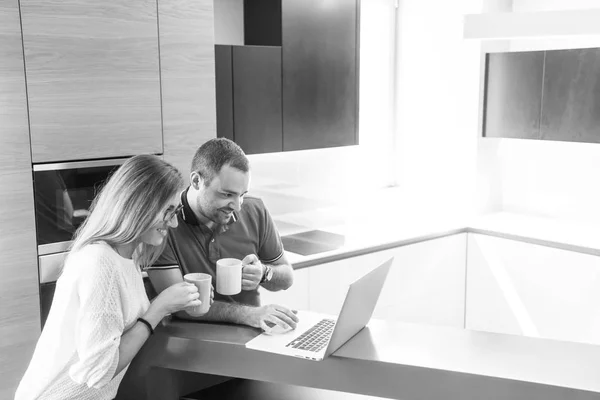 Пара пьет кофе и с помощью ноутбука дома — стоковое фото