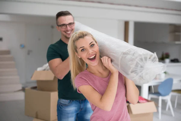 Casal carregando um tapete se mudando para casa nova — Fotografia de Stock
