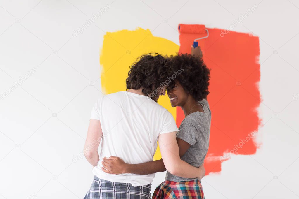 multiethnic couple painting interior wall