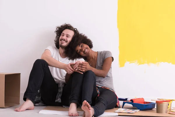 Jovem casal multiétnico relaxante após a pintura — Fotografia de Stock