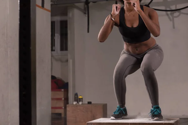 Nero donna sta eseguendo box salti a palestra — Foto Stock