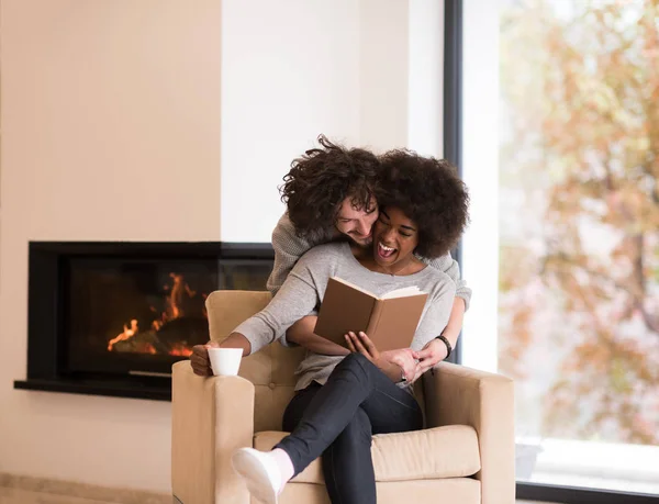 Pareja multiétnica abrazándose frente a la chimenea —  Fotos de Stock