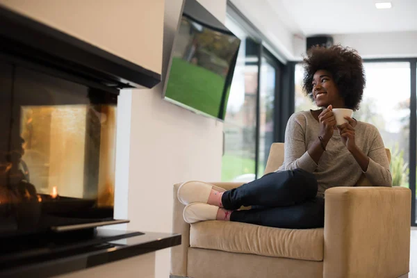 黒人女性の暖炉のそばでコーヒーを飲む — ストック写真