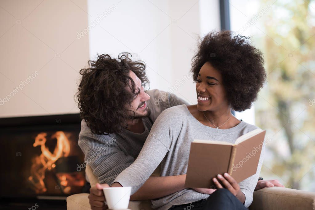multiethnic couple hugging in front of fireplace