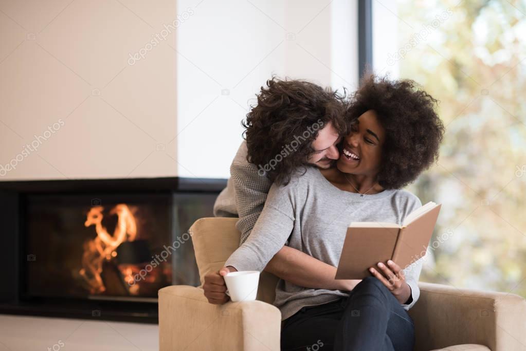 multiethnic couple hugging in front of fireplace