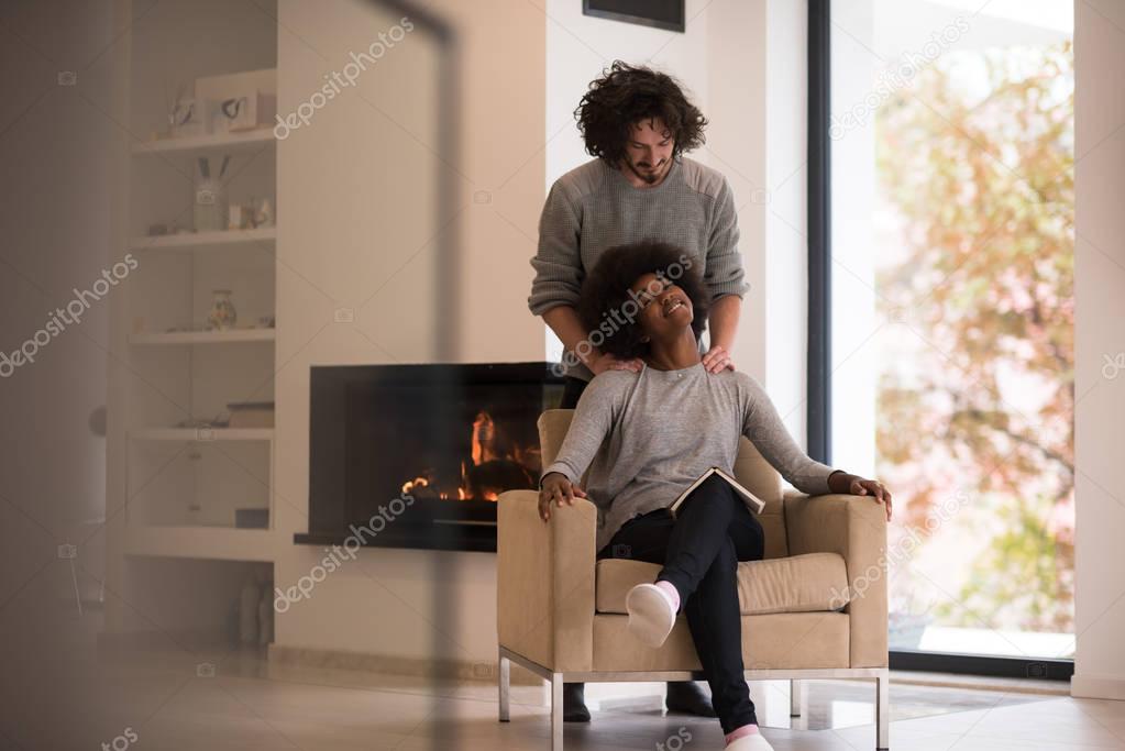 multiethnic couple hugging in front of fireplace